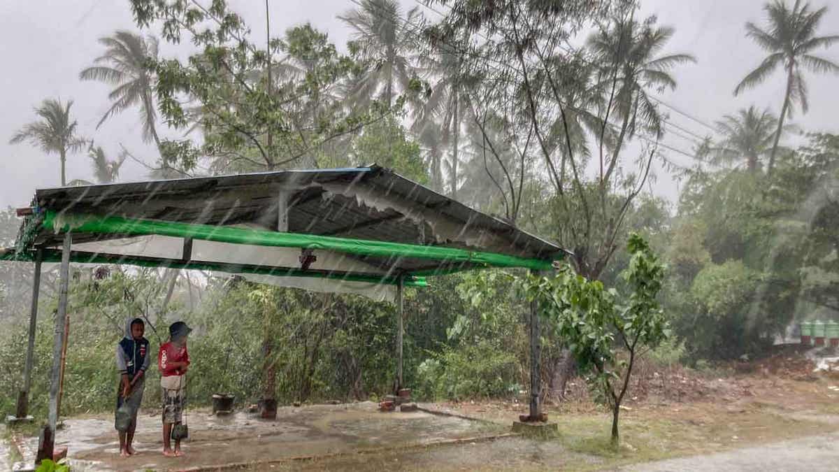 Two children stand under a roadside shelter 