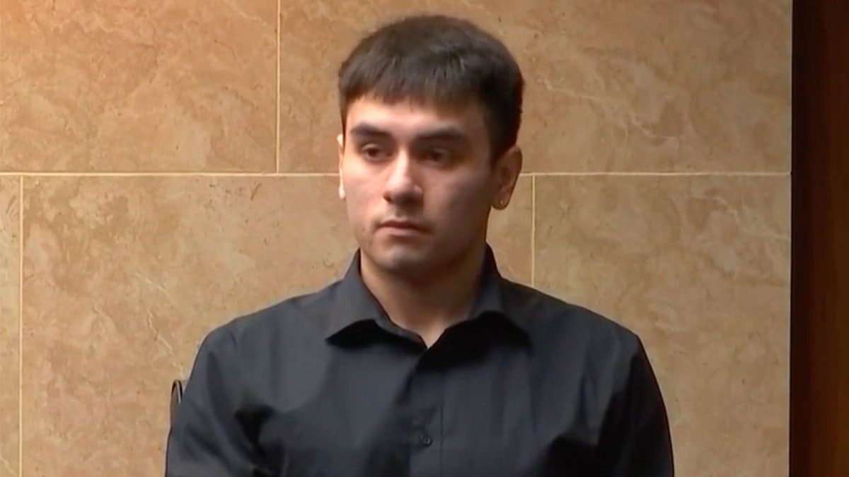 Austin Imirowicz sits in the witness box wearing button-down black shirt.
