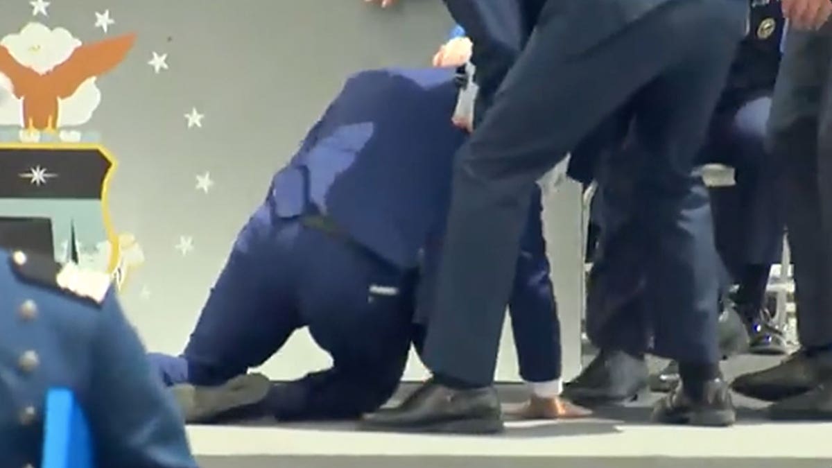 President Biden is pictured on the floor after tumbling at the ceremony.