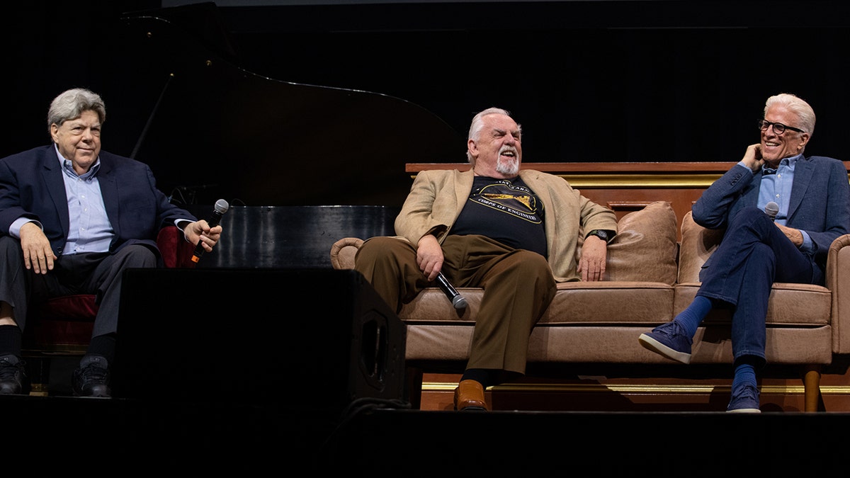 George Wendt in a chair and John Ratzenberger and Ted Danson seated on a couch, all laugh on stage at the ATX TV Festival