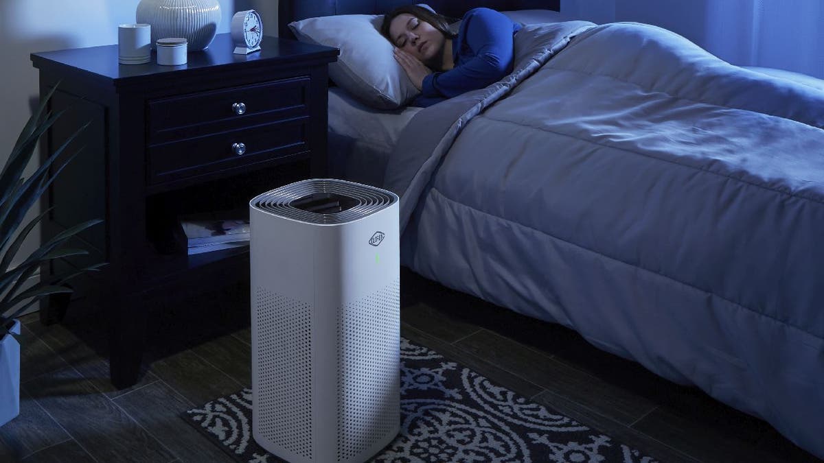 Woman sleeps in bed while her Clorox Large Room True HEPA Air Purifier runs next to her.