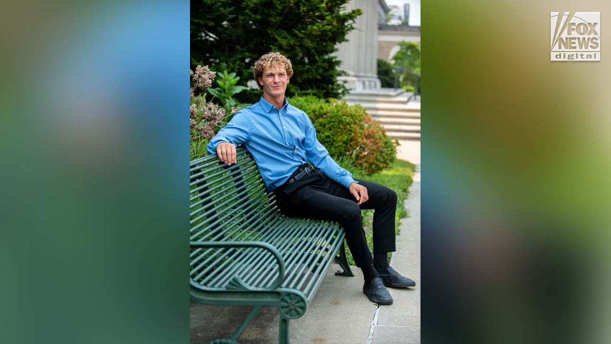 Daniel Penny poses for a photo on a bench