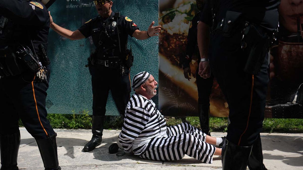 A demonstrator is surrounded by police after running in front of a motorcade of vehicles carrying former US President Donald Trump, at Wilkie D. Ferguson Jr. United States Federal Courthouse, in Miami, Florida, on June 13, 2023. 