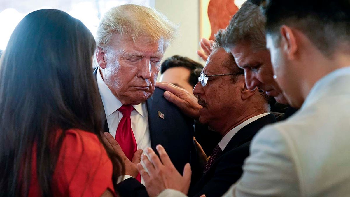 Donald Trump prays with supporters at Versailles restaurant