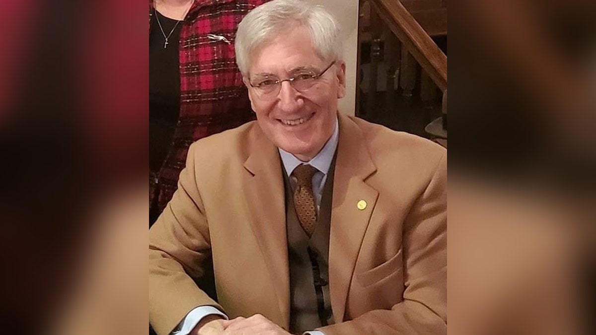 Dr. Robert P. George smiling in a tan suit