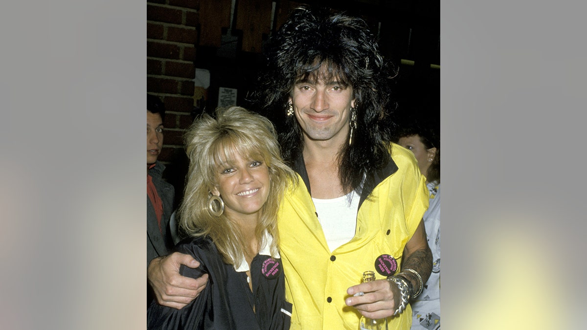 Heather Locklear smiles as Tommy Lee in a yellow shirt wraps his arm around her at the Calabasas Country Club