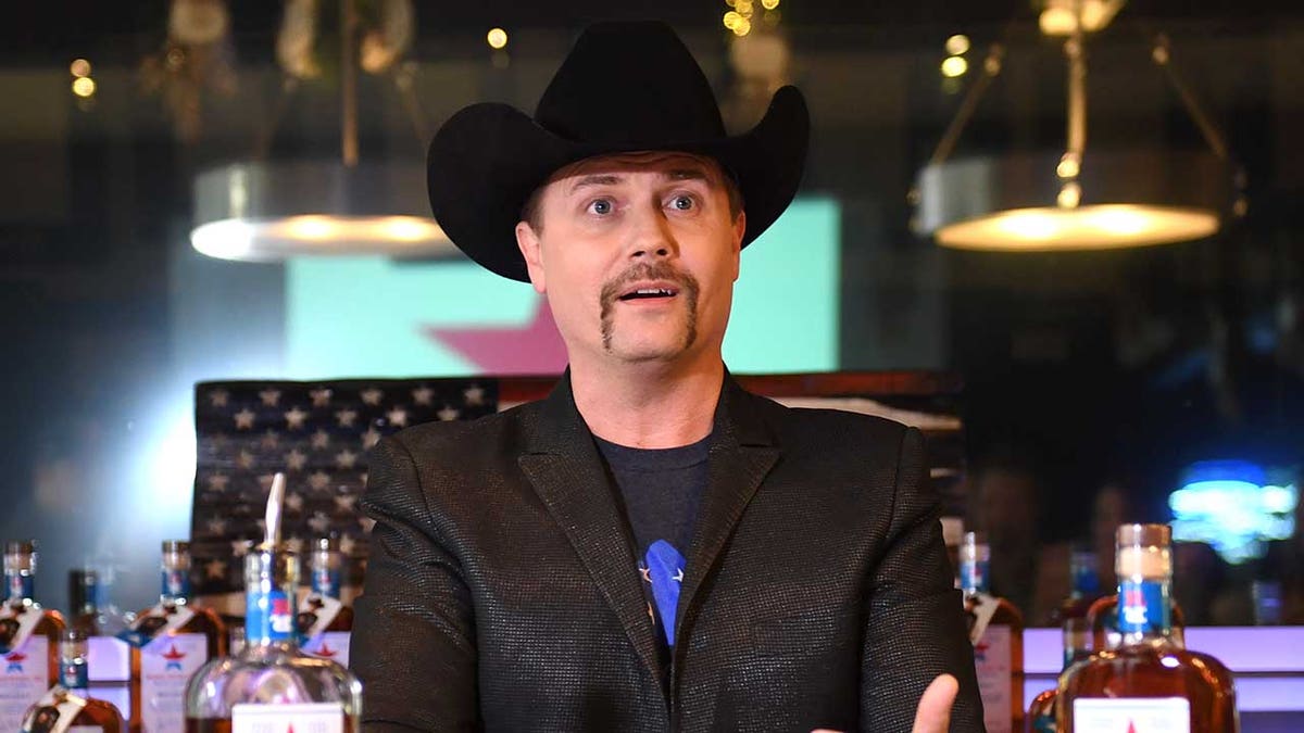John Rich in a black suit and cowboy hat at Mount Richmore in Nashville