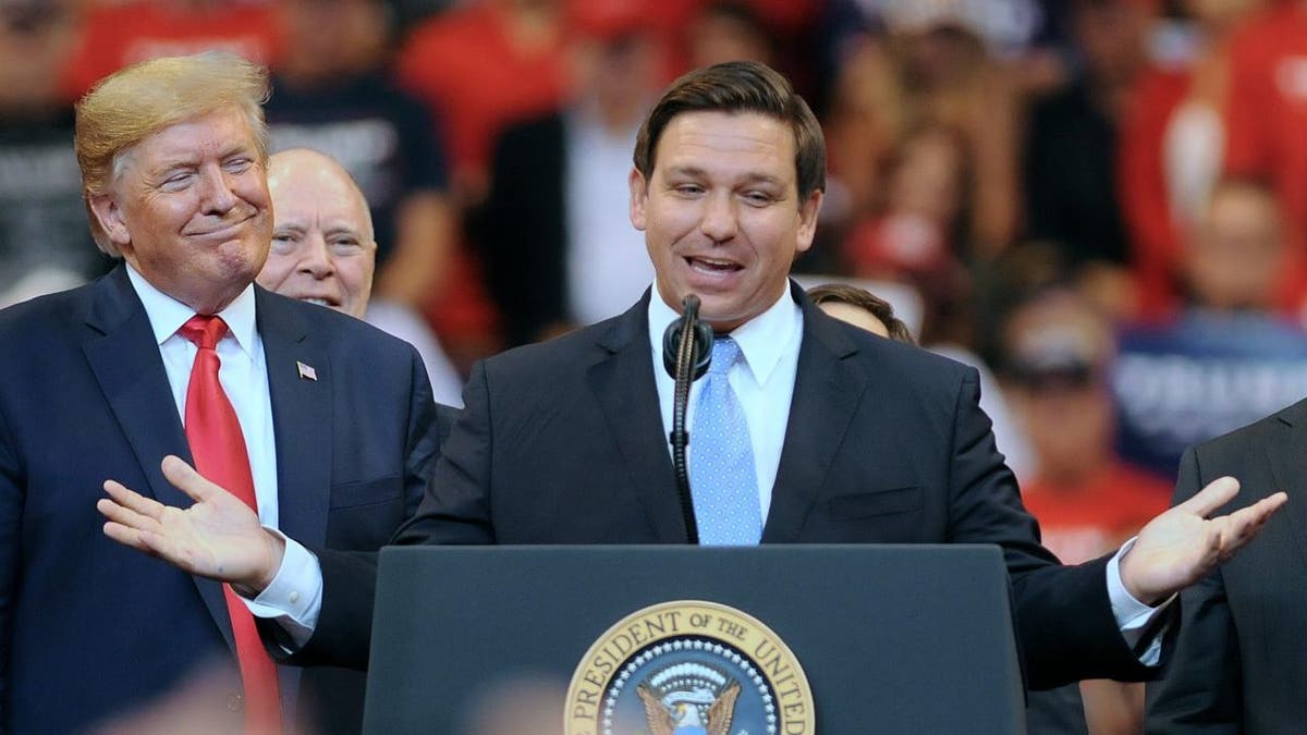 President Donald Trump looks on as Florida Governor Ron DeSantis speaks