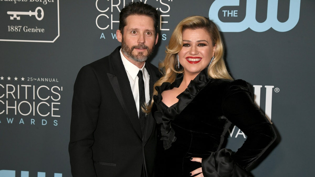 Kelly Clarkson smiles on the red carpet at the Critics Choice Awards with husband Brandon Blackstock