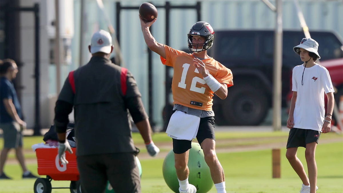 Tom Brady throws a pass as his son looks on