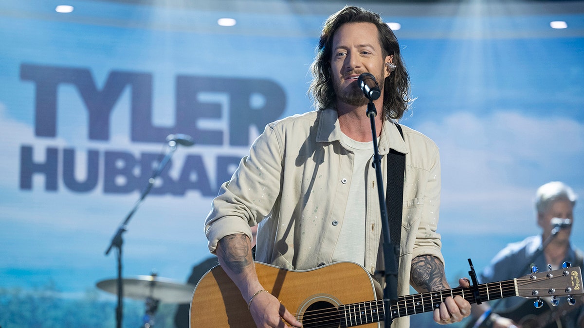 Tyler Hubbard on the Today show wearing a cream jacket and strumming the guitar
