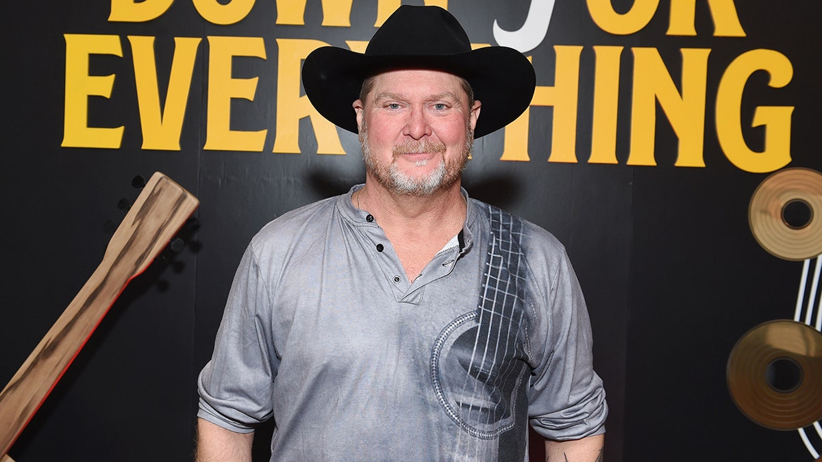 Tracy Lawrence smiles wearing a black cowboy hat ahead of the CMAs