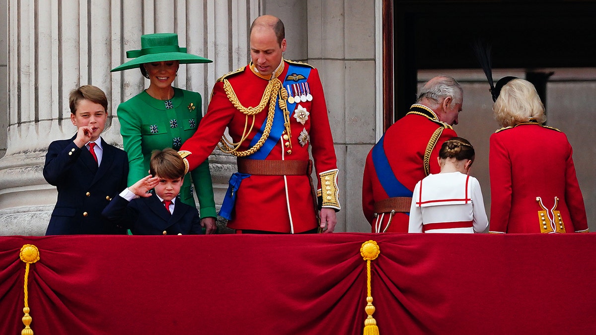 Prince William appeared to grab his son as he made a salute to the crowd as the king and queen entered Buckingham Palace.