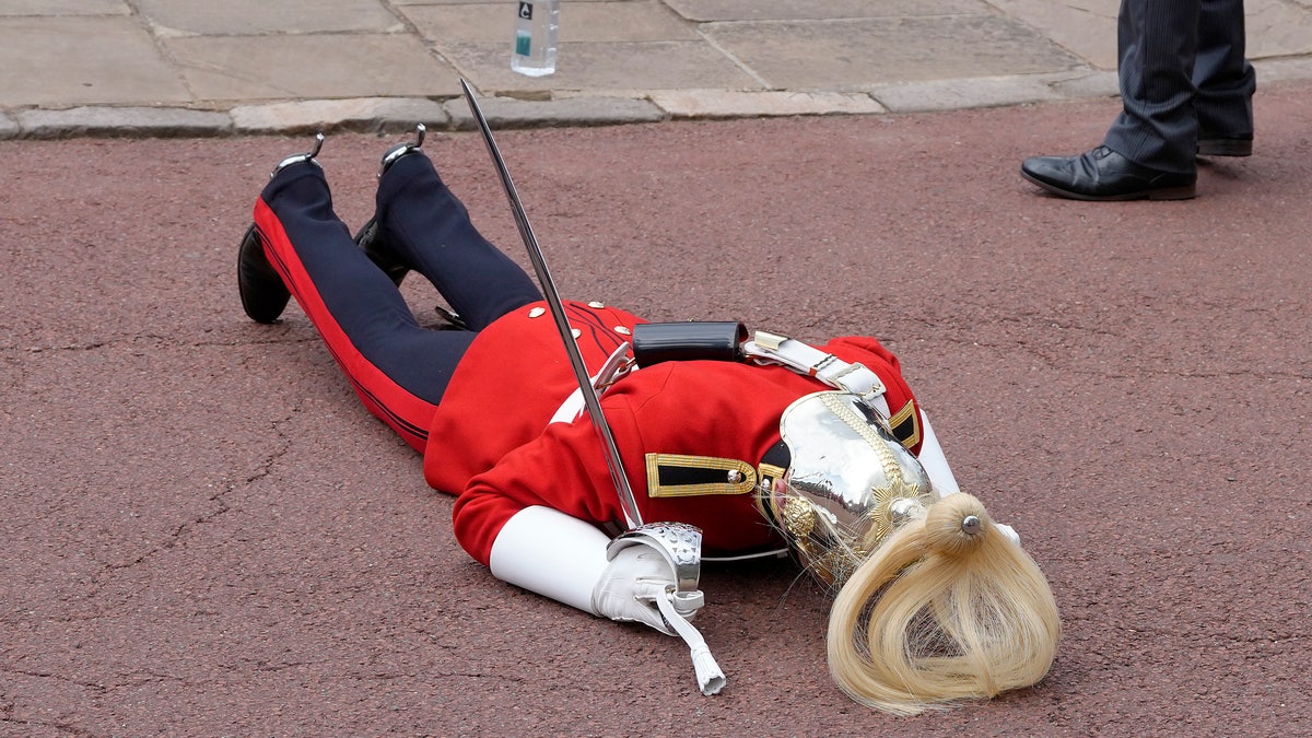 A member of the British military laying on the ground after fainting.