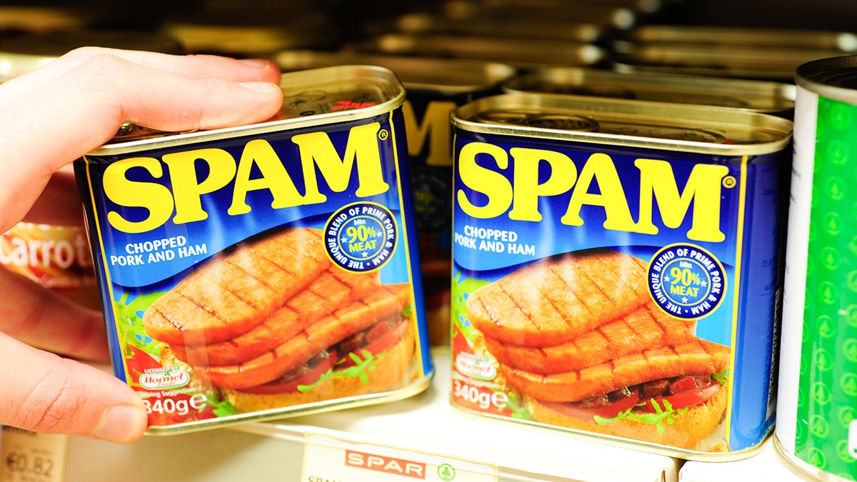 Can of spam on grocery shelf being held by person