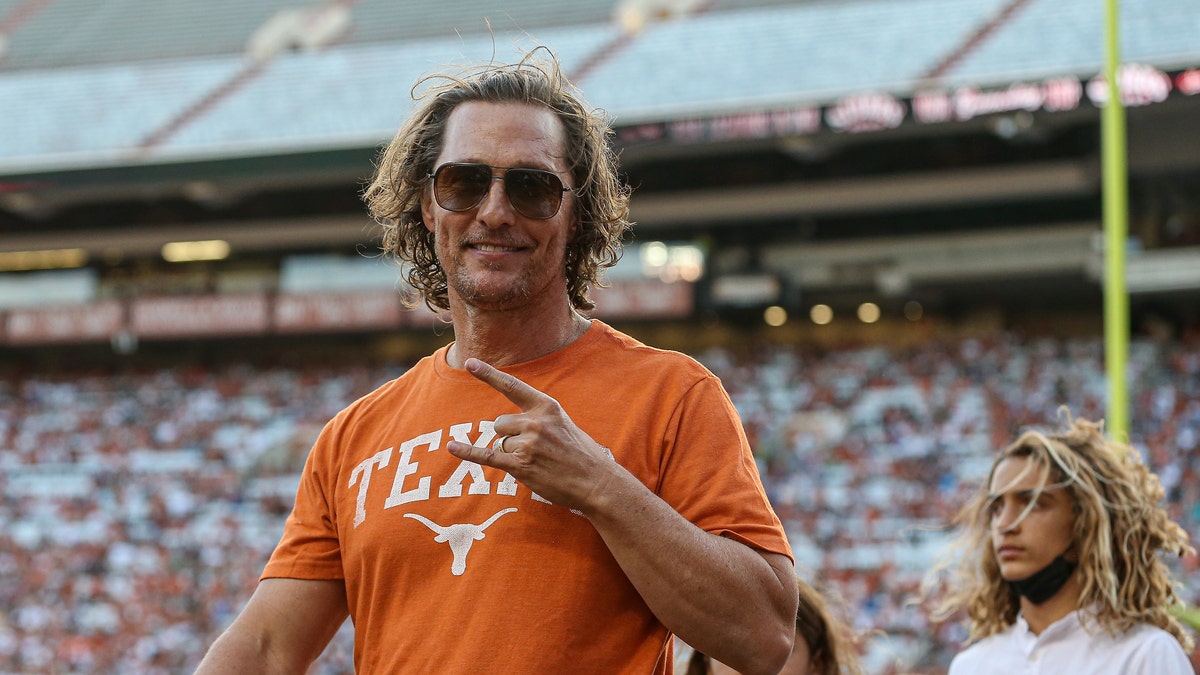 Matthew McConaughey wearing a Texas longhorns t-shirt and flashing the longhorns hand gesture