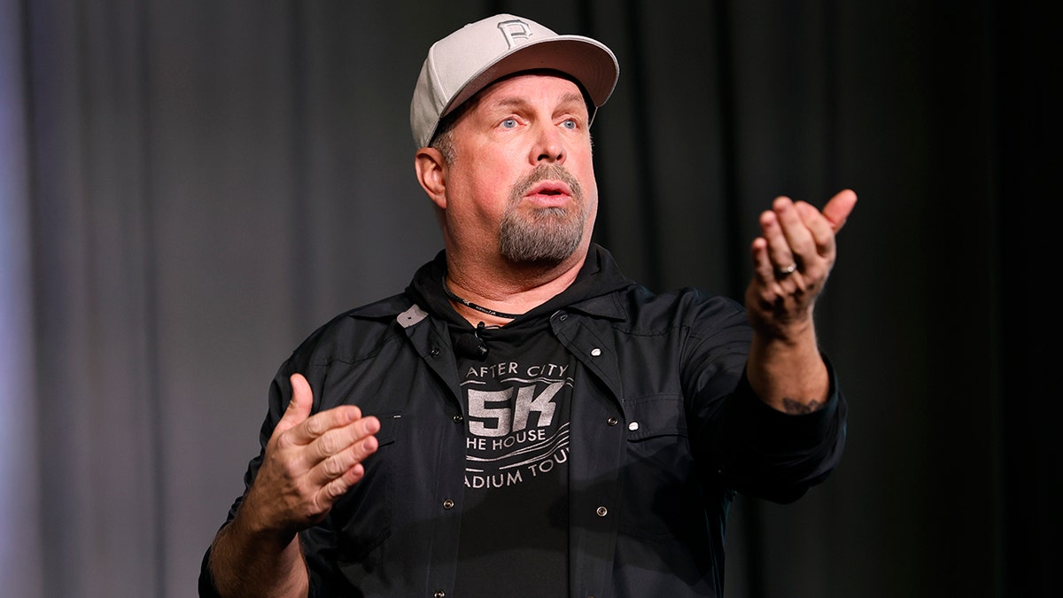 Garth Brooks wearing a hat and motioning to a crowd