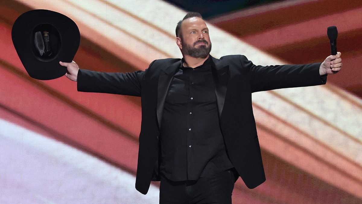 Garth Brooks at the CMAs holds out his arms as to take a bow