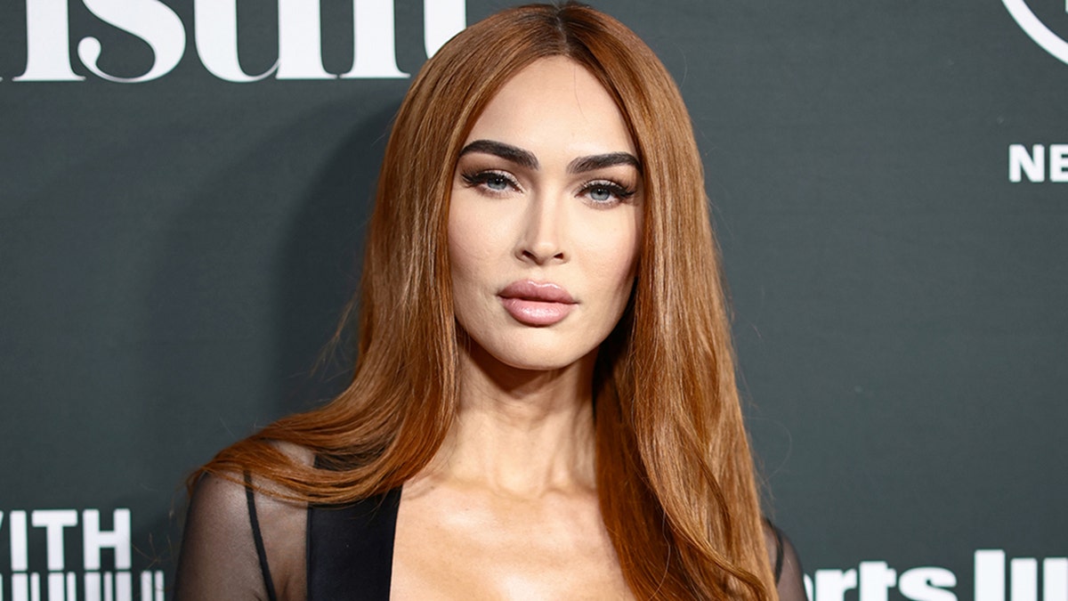 Megan Fox with red hair poses on the red carpet for the Sports Illustrated Swimsuit Issue release party in NYC
