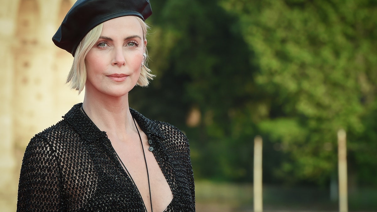 Charlize Theron in a black beret and black dress.