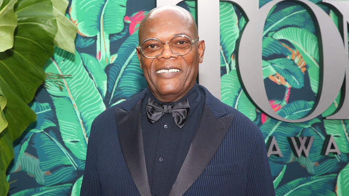Samuel L Jackson smiles in a navy suit on the Tony Awards red carpet in New York