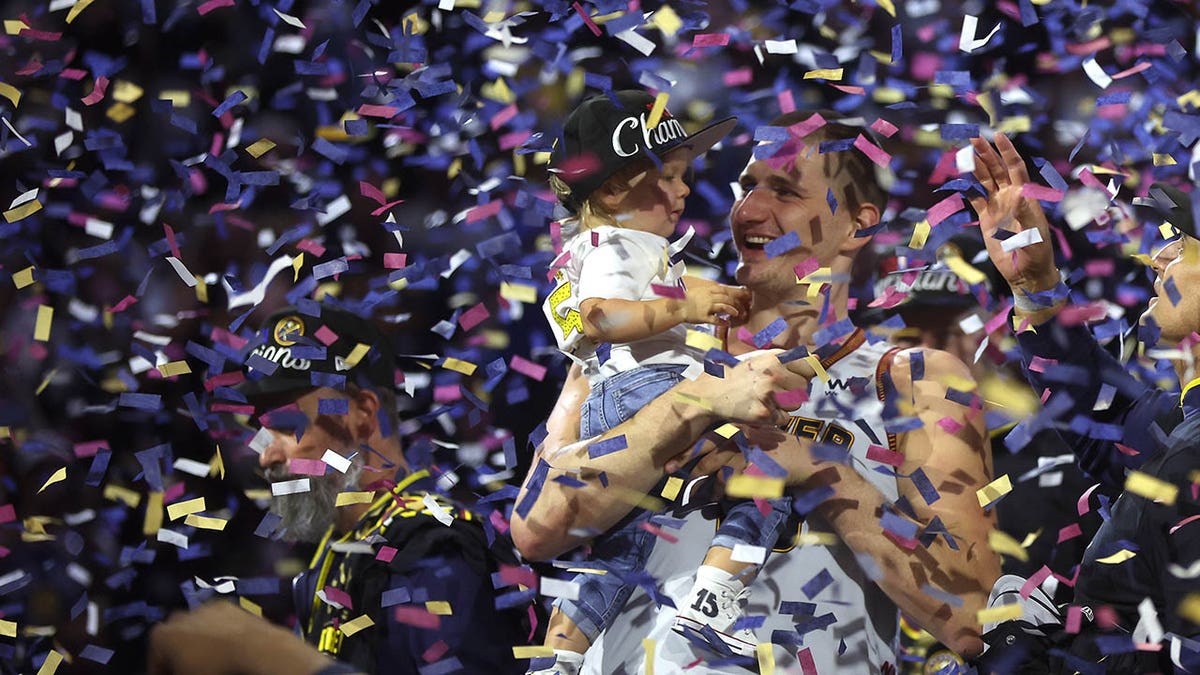 Nikola Jokic celebrates with his son after winning the NBA Championship