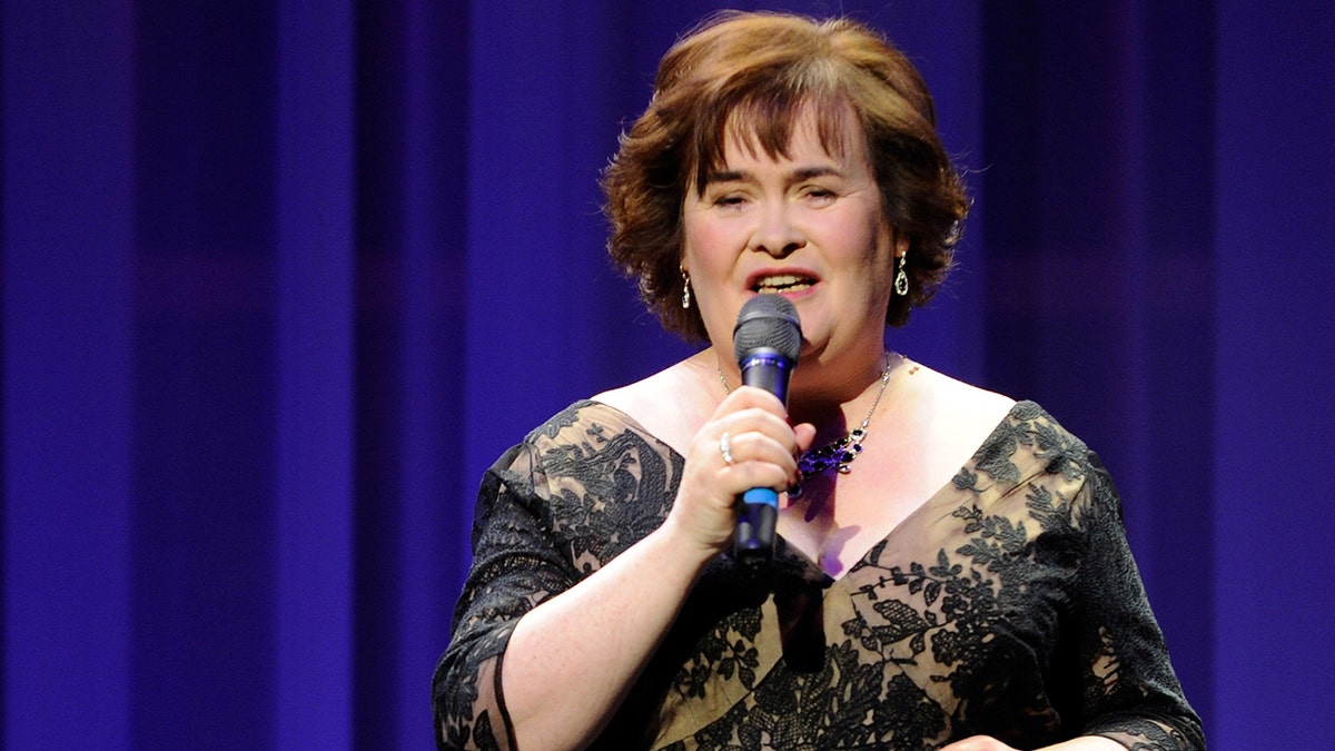 Susan Boyle in an off-shoulder gown sings into the microphone in Las Vegas