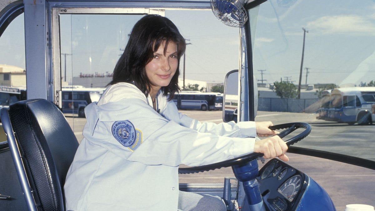A photo of Sandra Bullock behind the wheel of a bus.
