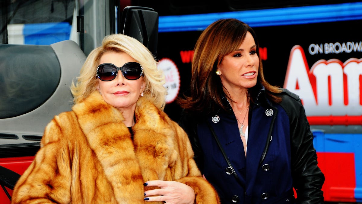 Joan Rivers in a fur coat and sunglasses with Melissa Rivers in a blue coat