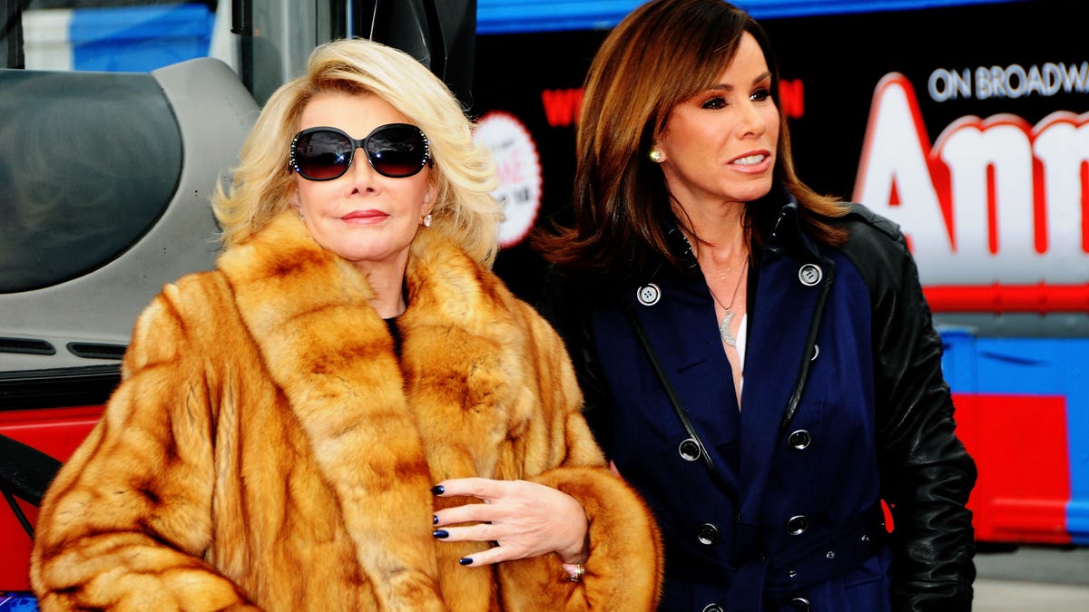 Joan Rivers in a fur coat and sunglasses with Melissa Rivers in a blue coat