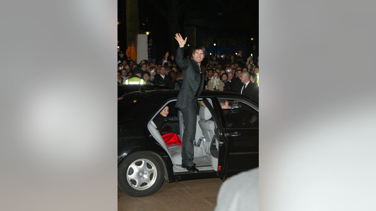 Tom Cruise waves to crowd from open car door with Penelope Cruz inside