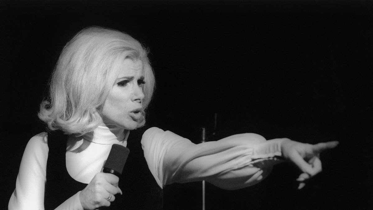 Black and white photo of Joan Rivers on stage pointing