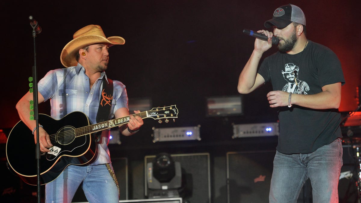 Jason Aldean performing onstage with Tyler Farr