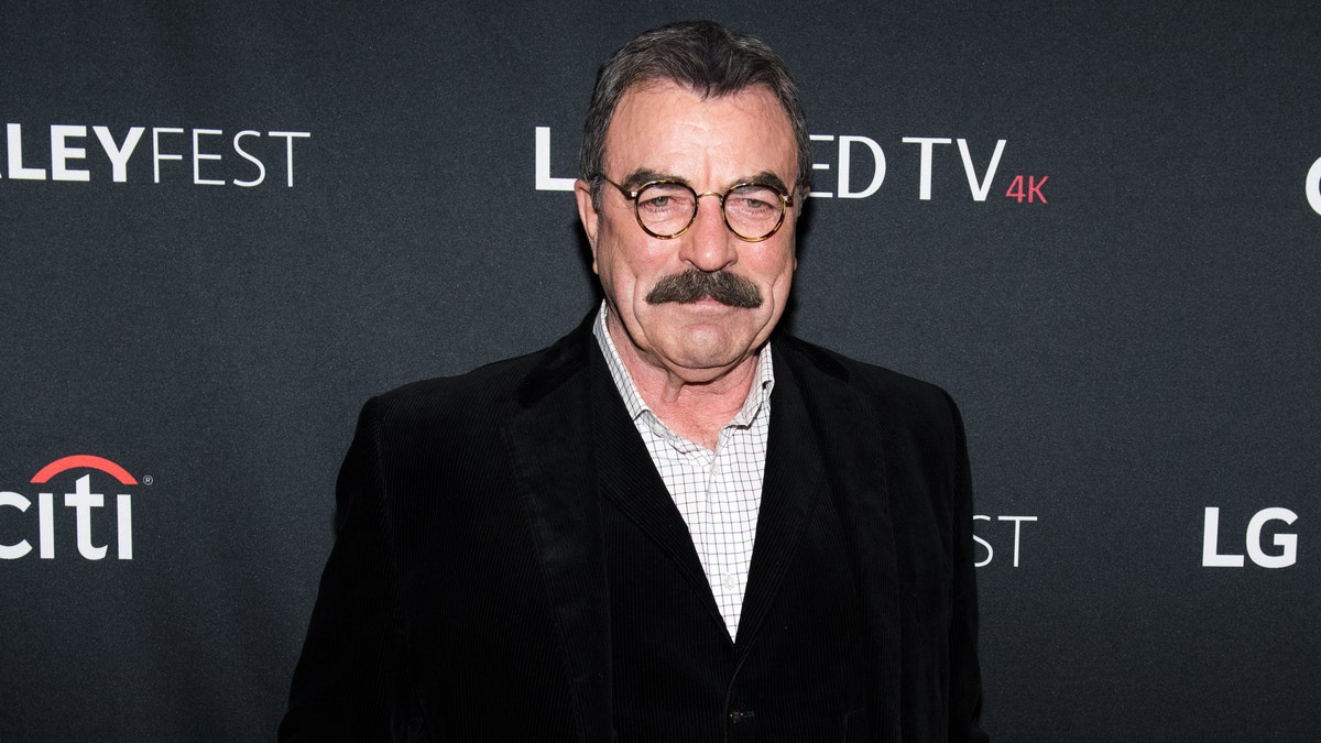 Tom Selleck looks stoic in the carpet in a black jacket