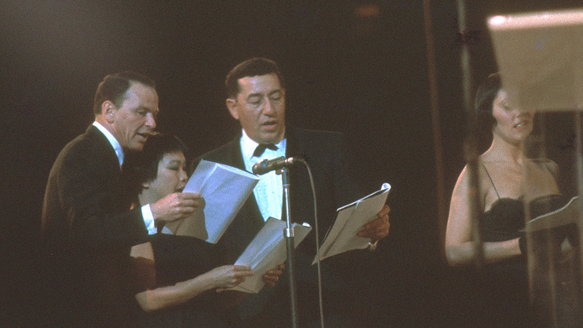 Frank Sinatra and Louis Prima performing alongside other musicians