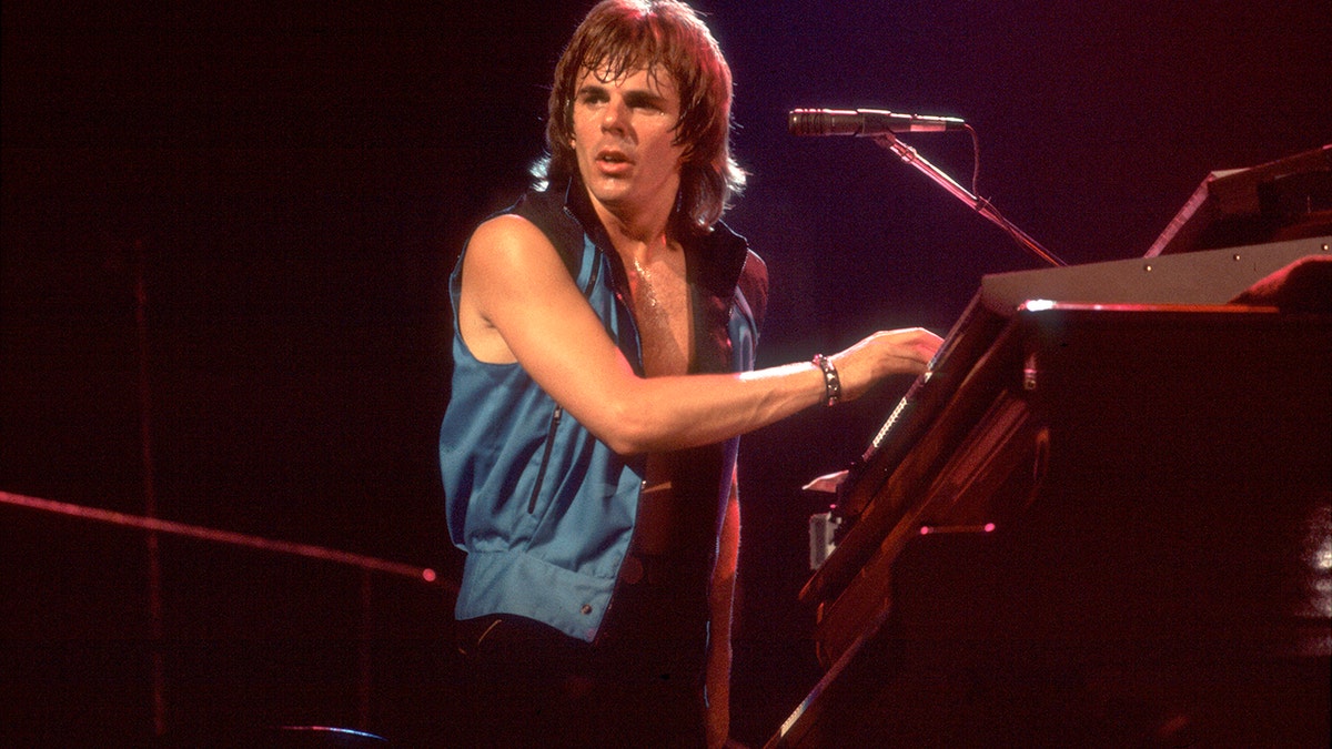 Jonathan Cain wearing a sleeveless blue shirt while playing the keyboard