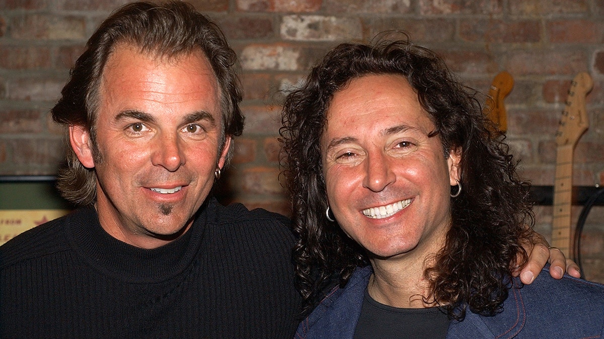 Jonathan Cain and Steve Augeri smiking in black shirts