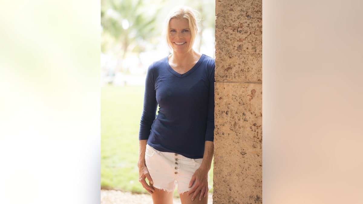 Mariel Hemingway in a long blue sleeved sweater and a white skirt