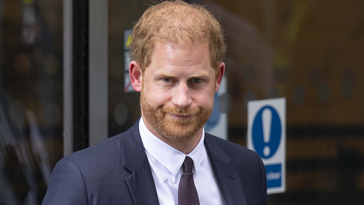 A close-up of Prince Harry looking stern in a dark suit