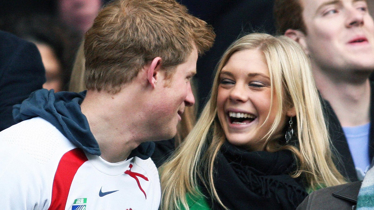 Prince Harry in a sports uniform laughing with Chelsy Davy wearing a scarf