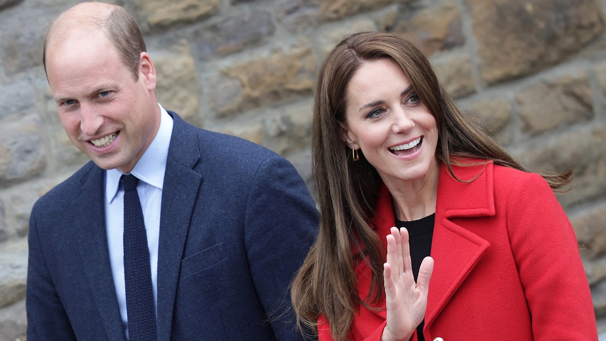 A close-up of Prince William in a blue suit and Kate Middleton wearing a red coat