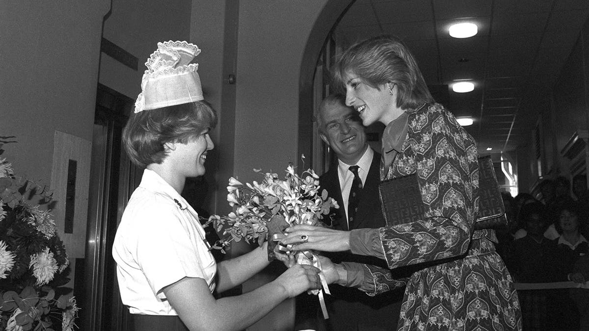 A black and white photo of Princess Diana receiving a bouquet of flowers from a nurse