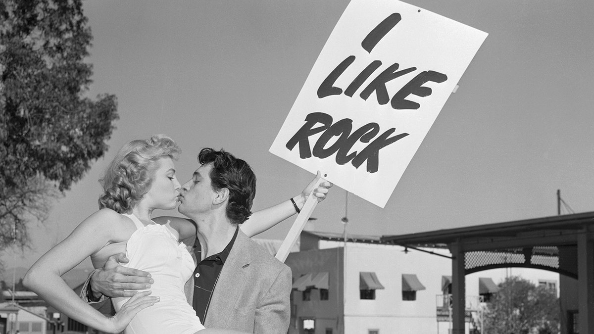 Rock Hudson gets a kiss from a woman holding an I Like Rock sign