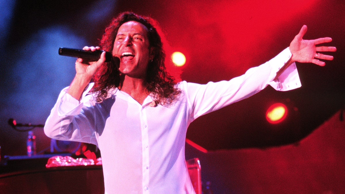 Steve Agueri in a white shirt performing on stage