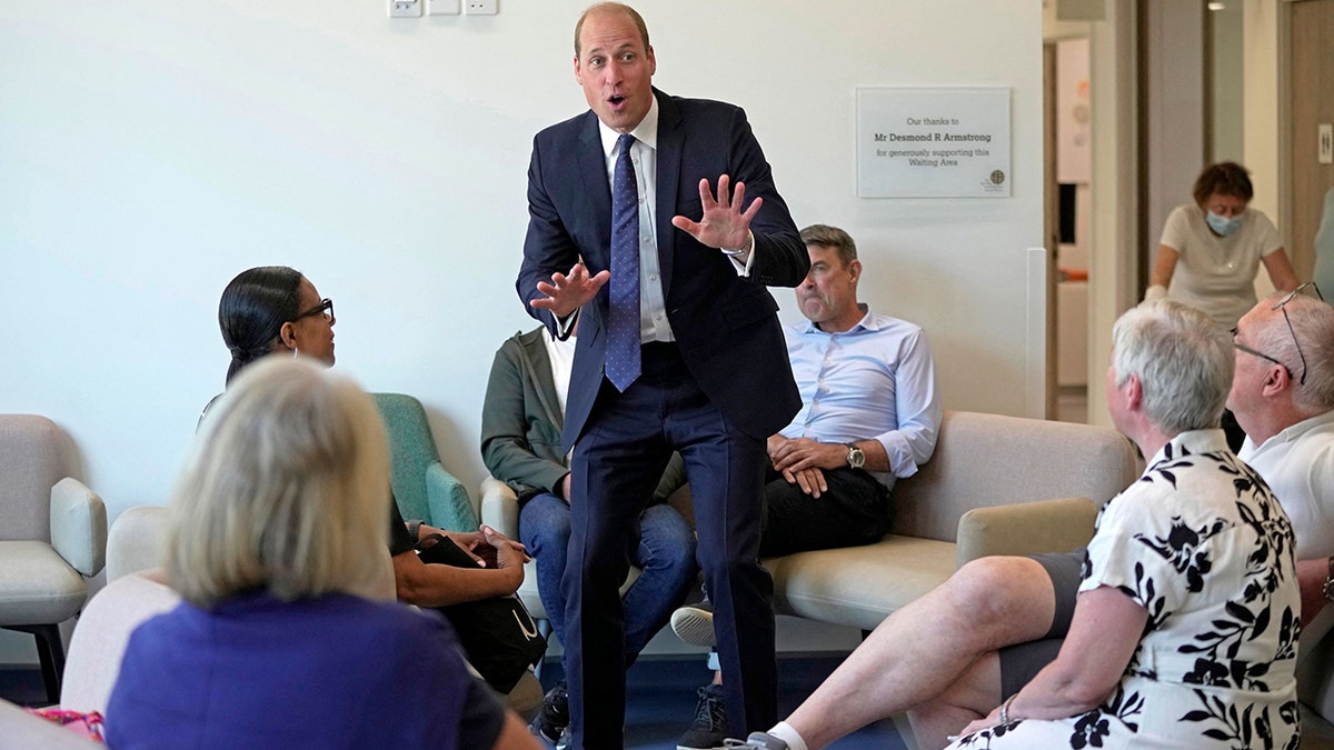 Prince William in a blue suit looking surprised at a cancer centre