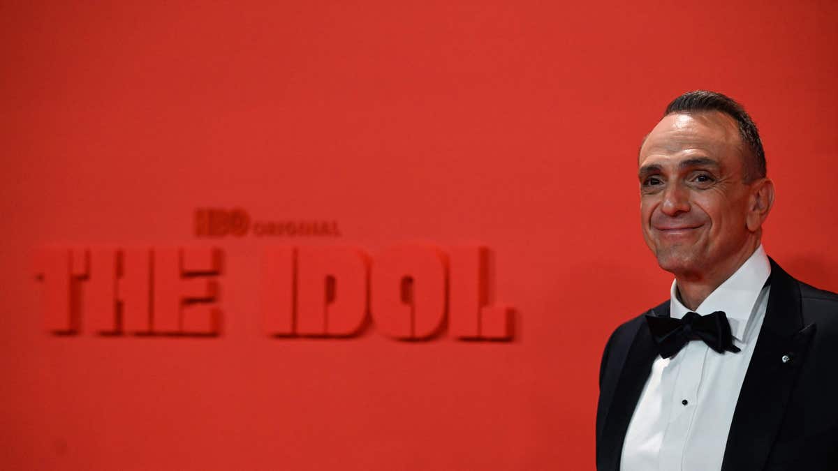 Hank Azaria poses by a sign that says "The Idol"