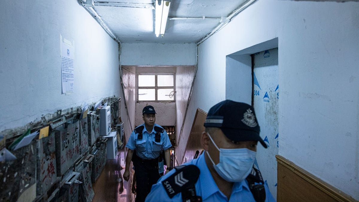 Police officers walk up an apartment where three children were killed in Sham Shui Po in Hong Kong, on June 5, 2023.