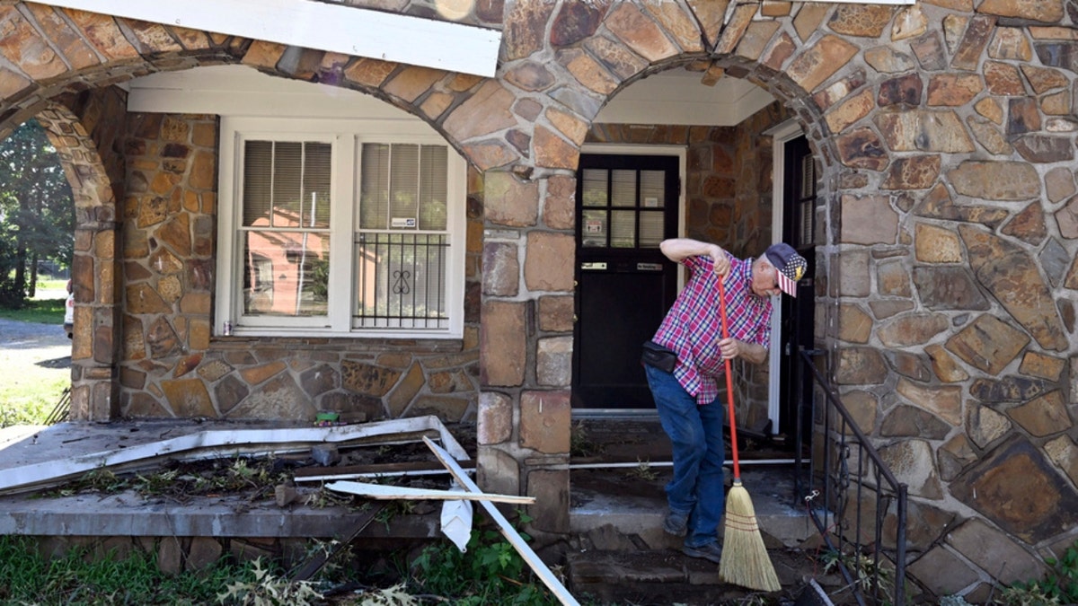 A man sweeps debris off of his front porch in North Little Rock, Arkansas