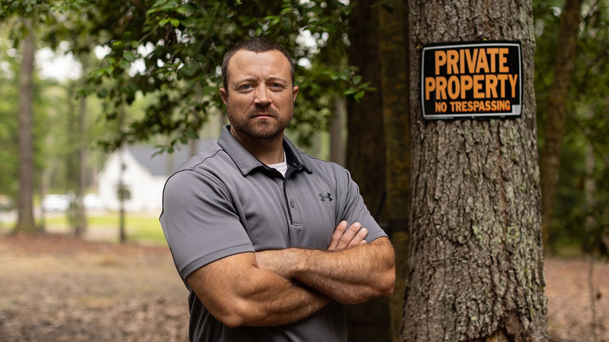 Virginia man stands in woods next to sign reading "private property"