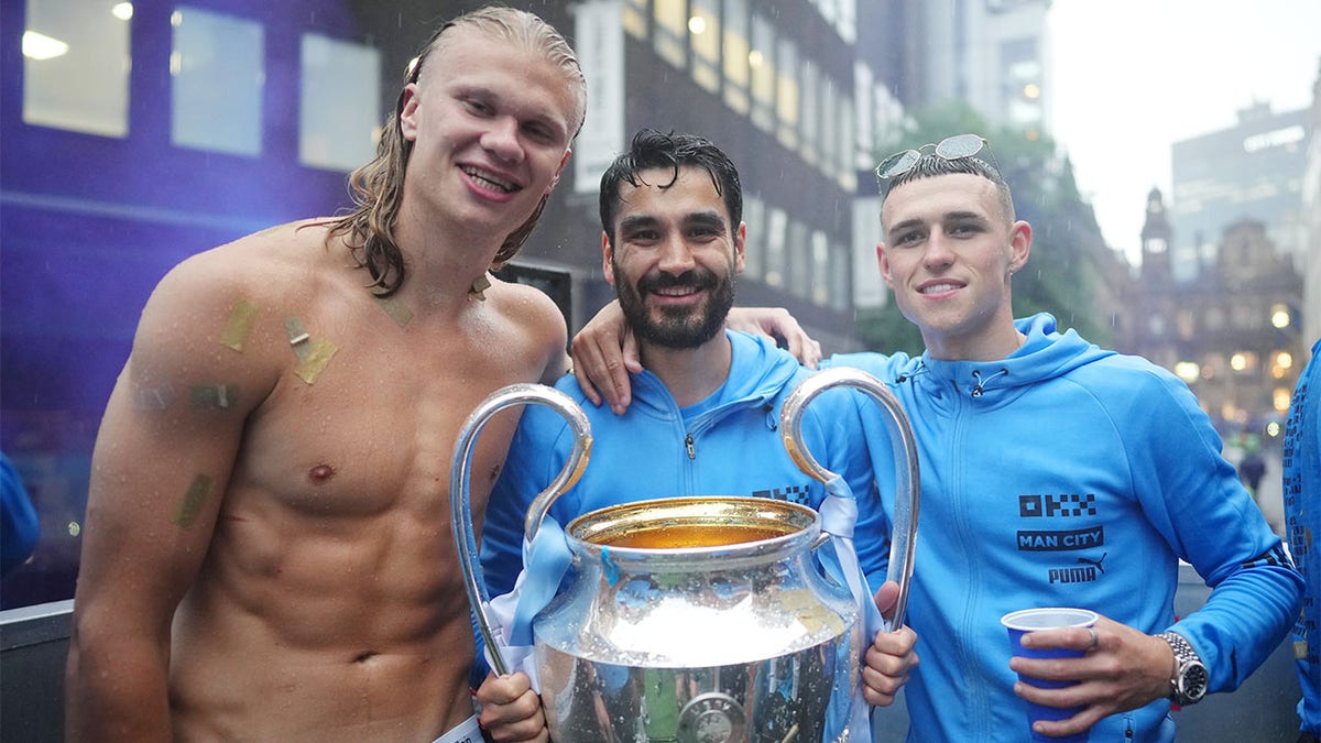 Erling Haaland of Manchester City poses for a photograph with Ilkay Guendogan and Phil Foden and the UEFA Champions League Trophy on the Open-Top Bus during the Manchester City trophy parade on June 12, 2023 in Manchester, England. 